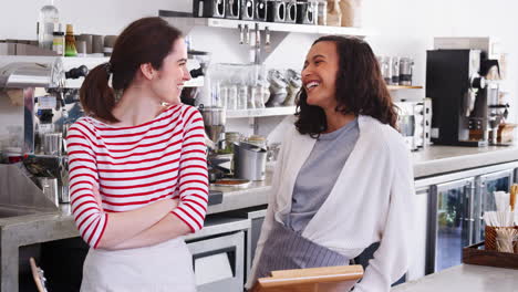 Two-female-coffee-shop-owners-smiling-behind-counter