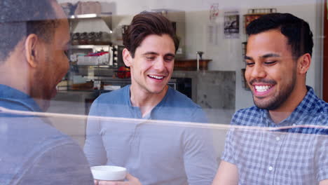 Three-male-friends-having-coffee-together-at-a-coffee-shop