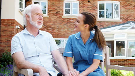 Senior-Man-Sitting-On-Bench-And-Talking-With-Nurse-In-Retirement-Home
