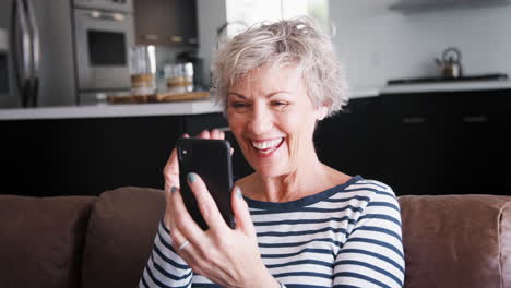 Senior-woman-video-calling-on-smartphone-at-home,-close-up