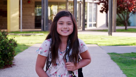Mixed-race-schoolgirl-walking-to-camera-smiling,-outdoors