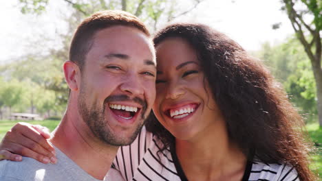 Outdoor-Head-And-Shoulders-Portrait-Of-Smiling-Couple-In-Park