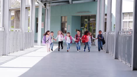 Elementary-school-kids-run-holding-hands-in-school-corridor