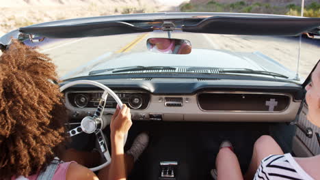 Two-female-friends-high-five-driving-in-an-open-top-car