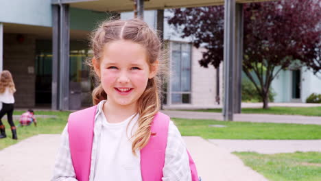 Elementary-schoolgirl-looking--to-camera-smiling,-outdoors