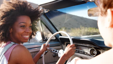 Two-female-friends-driving-in-an-open-top-car,-close-up