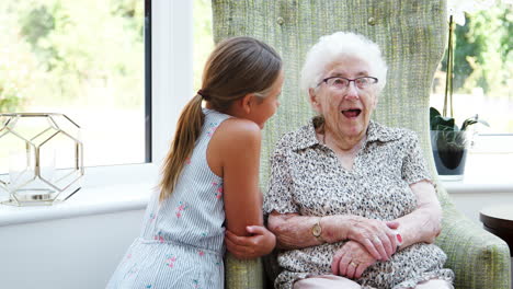 Granddaughter-Sitting-And-Talking-With-Grandmother-During-Visit-To-Retirement-Home