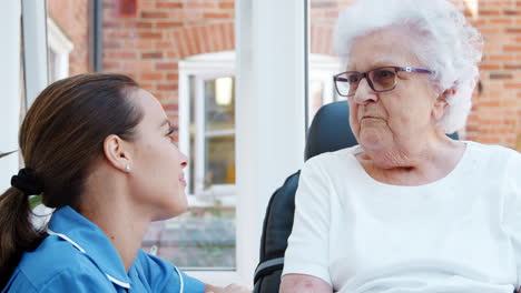 Ältere-Frau-Sitzt-Im-Motorisierten-Rollstuhl-Und-Spricht-Mit-Krankenschwester-Im-Altersheim