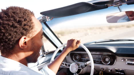 Black-man-driving-open-top-car-on-desert-highway,-close-up
