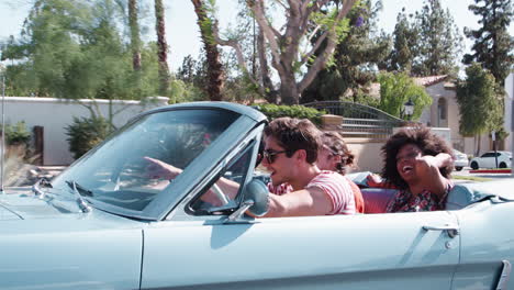 Happy-young-adult-friends-on-the-road-in-a-convertible