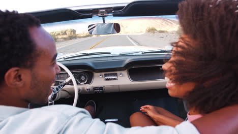 Young-black-couple-in-open-top-car-on-a-highway,-back-view