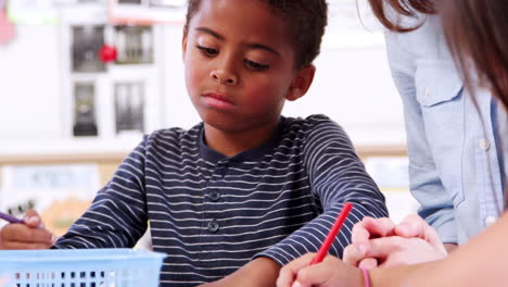 Teacher-helping-elementary-school-boy-in-art-class