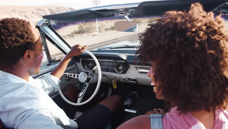 Young-black-couple-driving-open-top-car-on-a-desert-highway