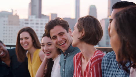 Friends-Standing-In-A-Line-Gathered-On-Rooftop-Terrace-For-Party-With-City-Skyline-In-Background