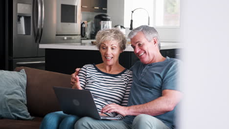 Senior-couple-on-the-couch-at-home-using-a-laptop-computer