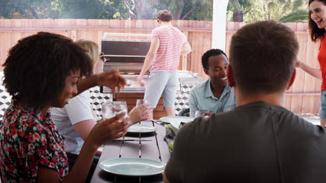 Young-adult-friends-sitting-outdoors-barbecuing