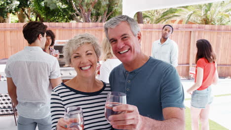 Senior-couple-at-a-backyard-party-raising-glasses-to-camera