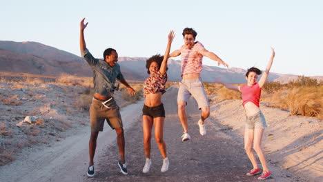 Young-adult-friends-jumping-in-the-air-on-a-desert-road