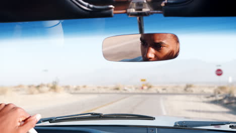 Young-black-man-driving-open-car,-seen-in-rear-view-mirror
