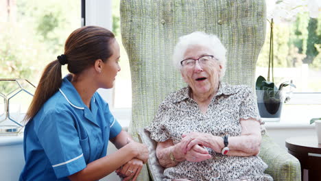 Senior-Woman-Sitting-In-Chair-And-Talking-With-Nurse-In-Retirement-Home