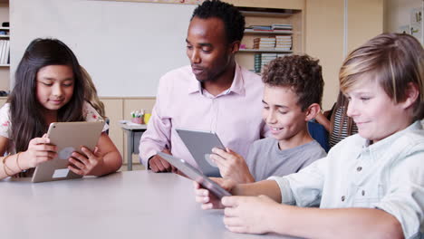 Teacher-among-kids-with-tablets-in-elementary-school-class
