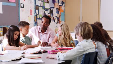 Teacher-working-with-elementary-school-kids-at-their-desk