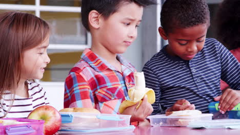 Niños-De-Escuela-Primaria-Comiendo-Almuerzos-Para-Llevar-En-Una-Mesa