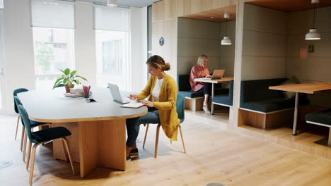 Zwei-Millennial-Frauen-Arbeiten-An-Laptops-Und-Sitzen-In-Einem-Kreativbüro,-In-Voller-Länge