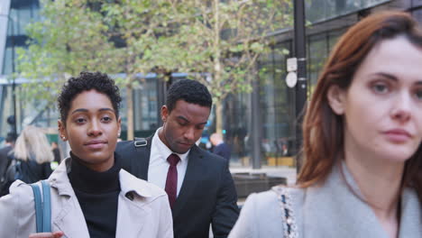 Three-millennial-business-people-walking-in-the-city-of-London,-close-up,-selective-focus