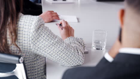 Detail-Of-Businessmen-And-Businesswomen-Making-Notes-At-Meeting-Around-Boardroom-Table