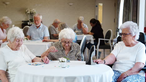 Group-Of-Seniors-Playing-Game-Of-Bingo-In-Retirement-Home