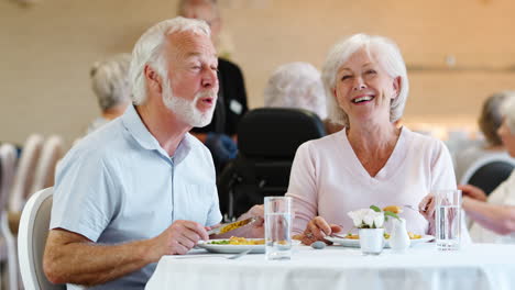 Senior-Couple-Eating-Meal-And-Talking-In-Retirement-Home