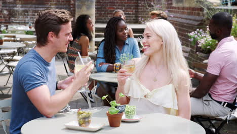 Young-Couple-Meeting-For-Drinks-At-Outdoor-Tables-In-Restaurant