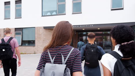 Rear-View-Of-Two-Female-High-School-Students-Walking-Into-College-Building-Together