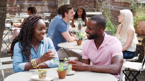 Young-Couple-Meeting-For-Drinks-At-Outdoor-Tables-In-Restaurant