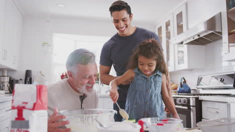 Young-Hispanic-girl-baking-with-grandfather-and-father-in-the-kitchen-filling-cake-forms,-close-up
