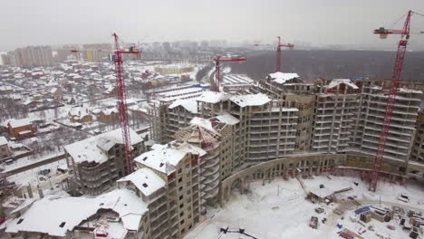 Flying-over-suburbs-of-winter-city-and-construction-site-of-apartment-complex