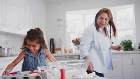 Excited-young-girl-and-her-grandmother-baking-high-five-and-put-cakes-in-the-oven-to-cook,-close-up
