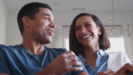 Happy-African-American-couple-sitting-on-the-sofa-watching-TV-and-eating-popcorn,-close-up,-low-angle