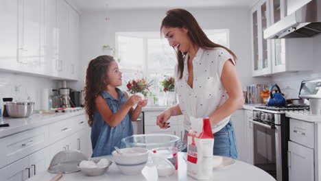 Jump-cut-clip-of-mother-and-young-daughter-preparing-cake-mix-and-baking-cakes-in-their-kitchen