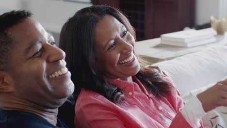Happy-middle-aged-African-American-couple-sitting-together-on-the-sofa-watching-TV,-close-up,-elevated-view