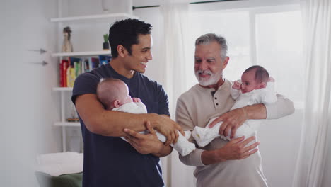 Young-Hispanic-man-and-his-senior-father-holding-his-two-baby-boys-at-home,-close-up