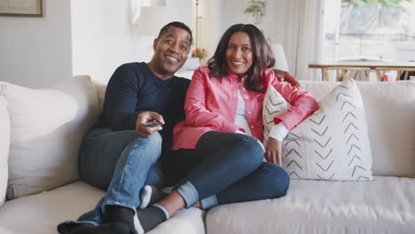 Middle-aged-African-American-couple-reclining-on-the-sofa-in-their-living-room-watching-TV,-full-length