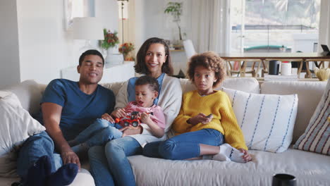Young-African-American-family-relaxing-on-sofa-watching-TV-together-at-home