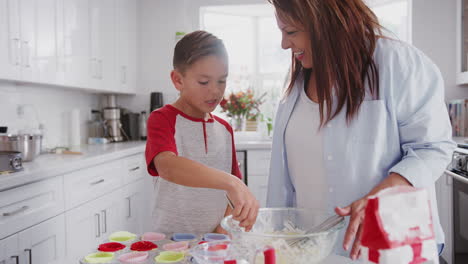 Happy-pre-teen-Hispanic-boy-and-his-grandmother-baking-cakes-in-kitchen-high-five-and-hug,-close-up
