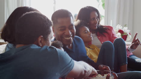 Drei-Generationen-Einer-Afroamerikanischen-Familie,-Die-Auf-Dem-Sofa-Sitzt,-Fernsieht-Und-Gemeinsam-Popcorn-Isst,-Aus-Nächster-Nähe