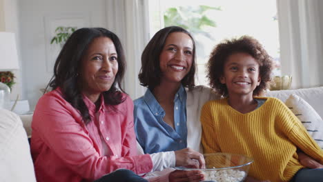 Drei-Generationen-Weibliche-Familiengruppe-Sitzen-Vor-Dem-Fernseher,-Lachen-Und-Essen-Popcorn,-Aus-Nächster-Nähe