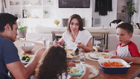 Young-Hispanic-family-sitting-at-dining-table-at-home-eating-dinner-together