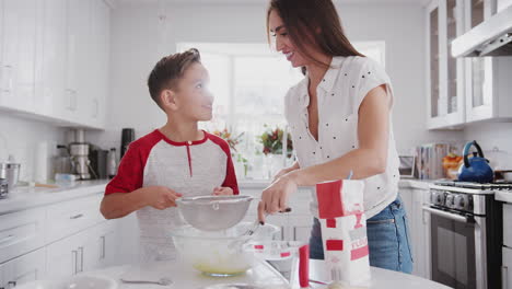 Pre-teen-Hispanic-boy-making-cake-mix-in-the-kitchen-with-his-mother,-close-up