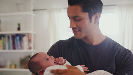 Hispanic-father-holding-his-four-month-old-son-and-rocking-him-gently,-head-and-shoulders,-close-up